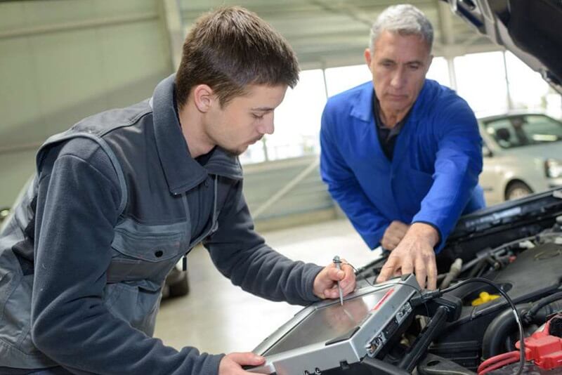 Dos personas de diferentes edades trabajando en el sector de la automoción