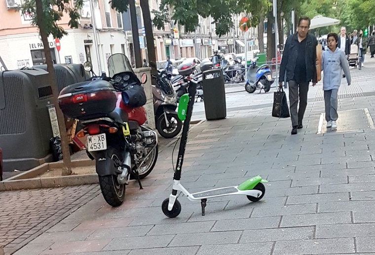 Un patinete mal aparcado en medio de una acera de Madrid