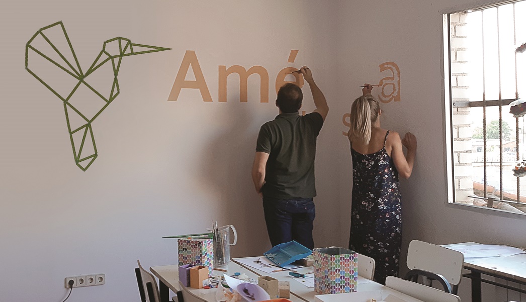 Dos empleados de Aecom trabajan como voluntarios decorando una pared 