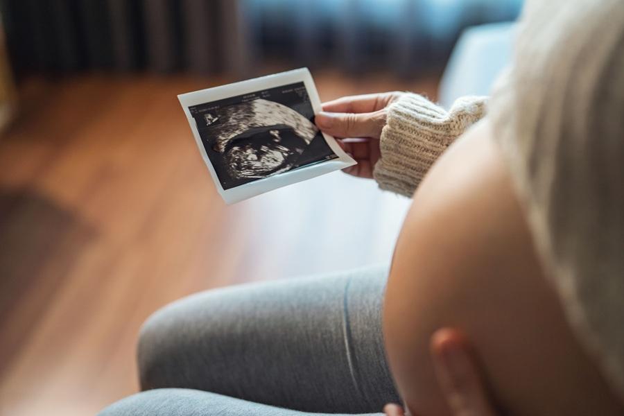 Mujer embarazada que mira su informe de ultrasonido.